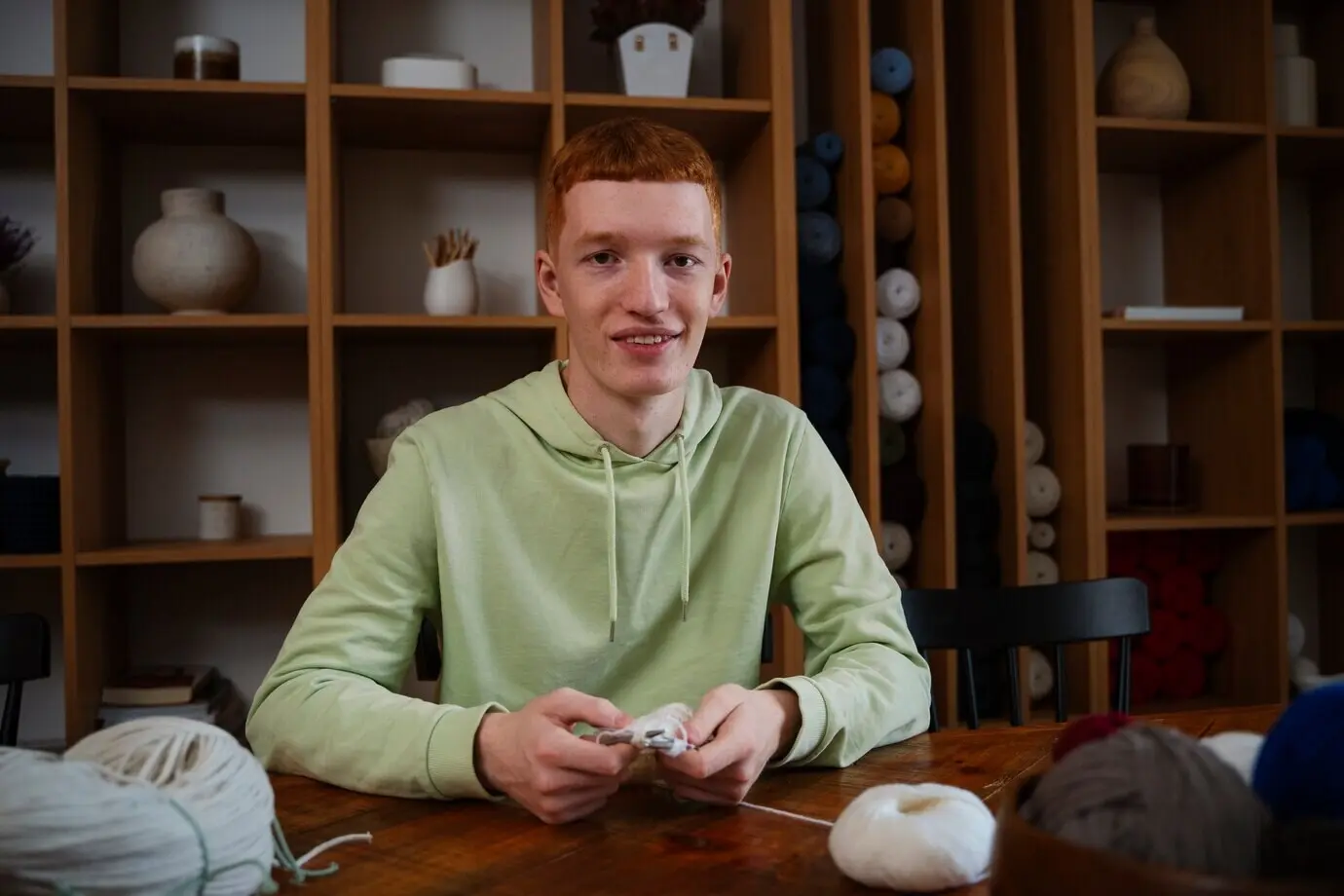 Halbtotale eines lächelnden Mannes beim Stricken